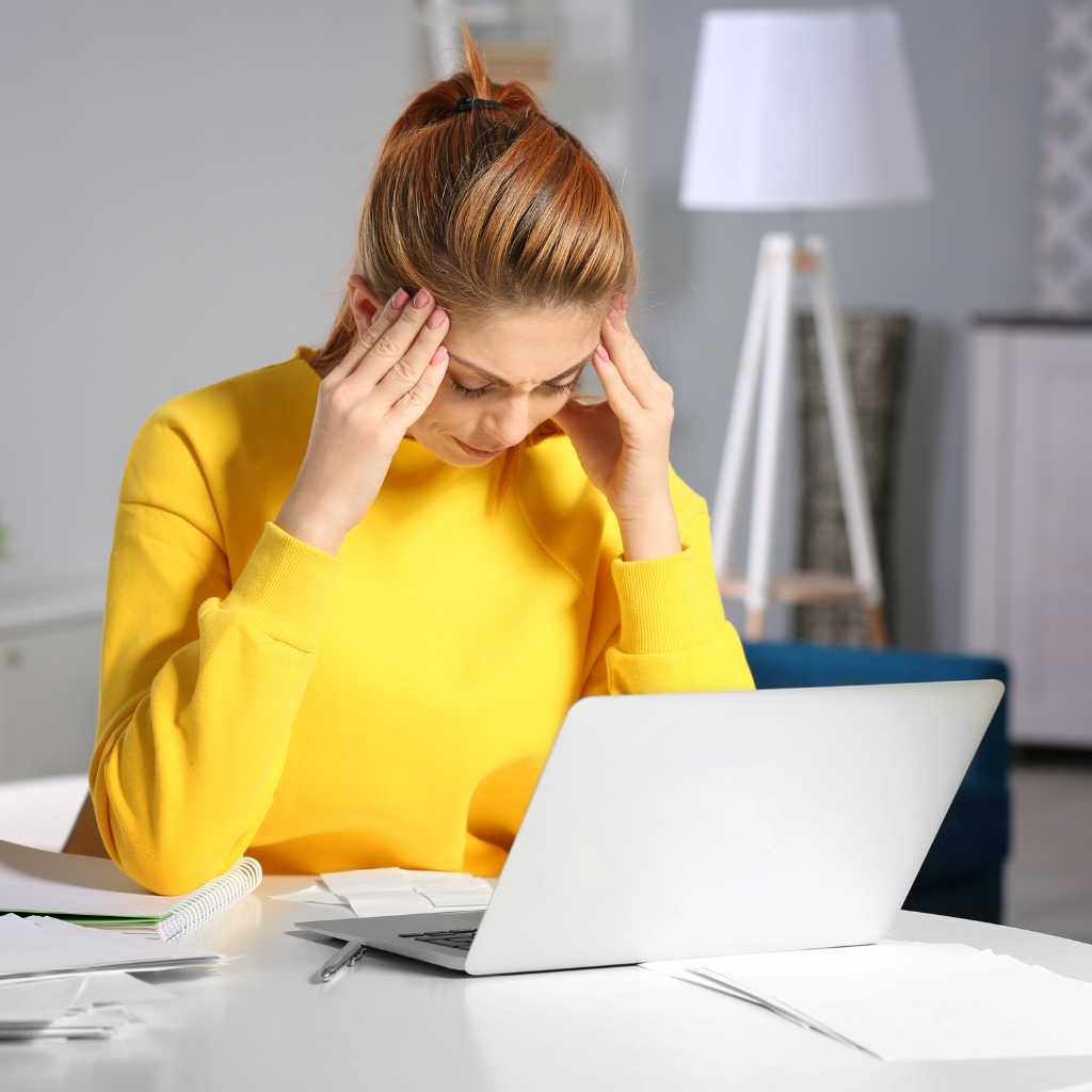 young, tired woman seated at a desk in front of computer