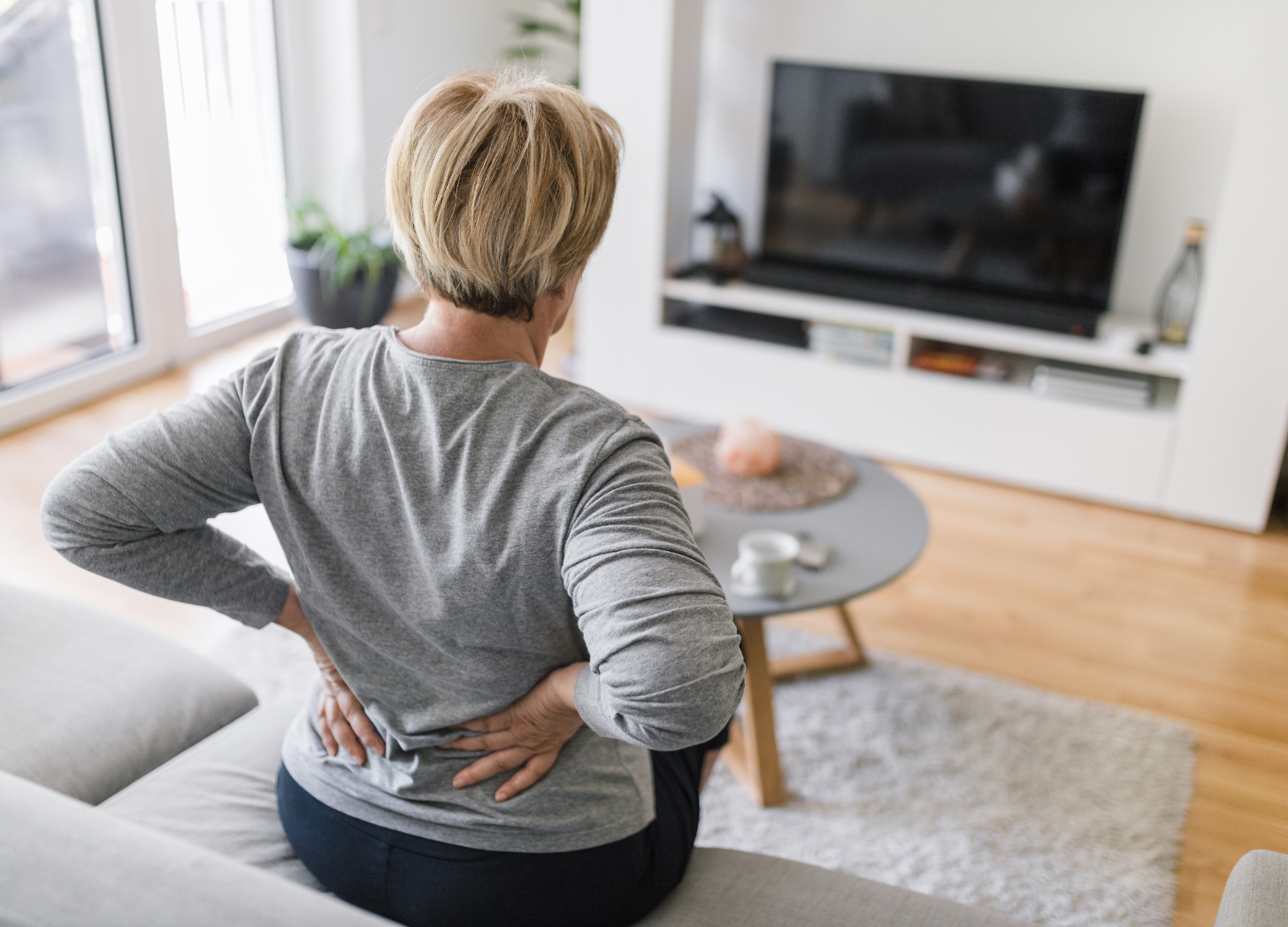 older woman holding her back as if in pain